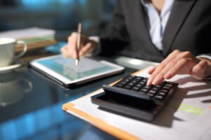 Businesswoman hands using tablet and calculator in the night