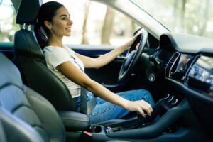 Young attractive woman driving, holding gear stick and smiling.